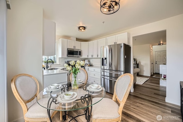 interior space with wood finished floors, light countertops, a sink, stainless steel appliances, and white cabinetry