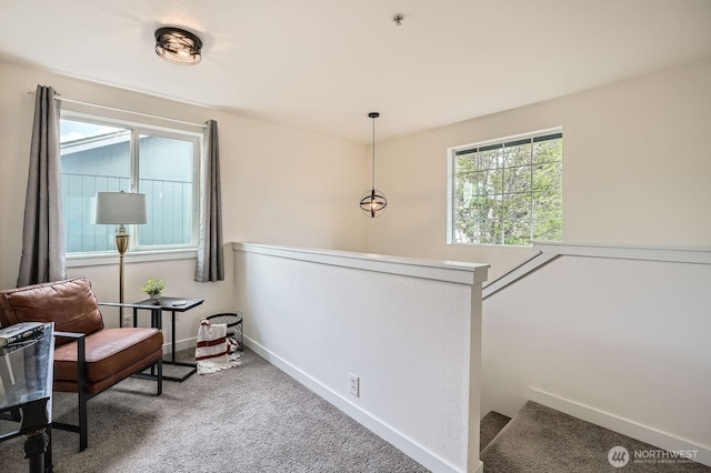 living area featuring carpet flooring, baseboards, and an upstairs landing
