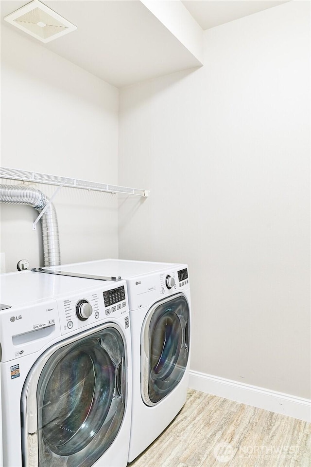 washroom with laundry area, visible vents, wood finished floors, baseboards, and washer and clothes dryer