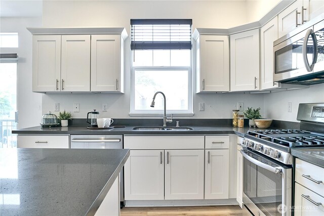 12310 NE 92nd St Unit H202, Kirkland, WA 98033 - kitchen featuring a sink, dark stone countertops, appliances with stainless steel finishes, and light wood finished floors