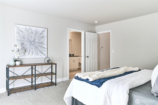 bedroom with baseboards, ensuite bathroom, and light colored carpet