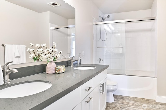 full bath featuring double vanity, toilet, a sink, and wood finished floors
