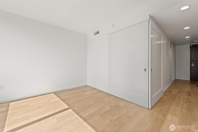 empty room with light wood-style floors, baseboards, and recessed lighting