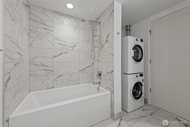 bathroom with stacked washer and clothes dryer, marble finish flooring, and shower / washtub combination