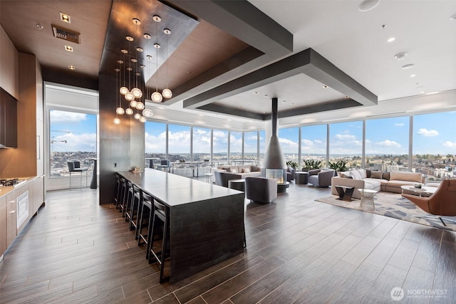 kitchen featuring dark wood finished floors, open floor plan, a wall of windows, stainless steel gas cooktop, and a tray ceiling