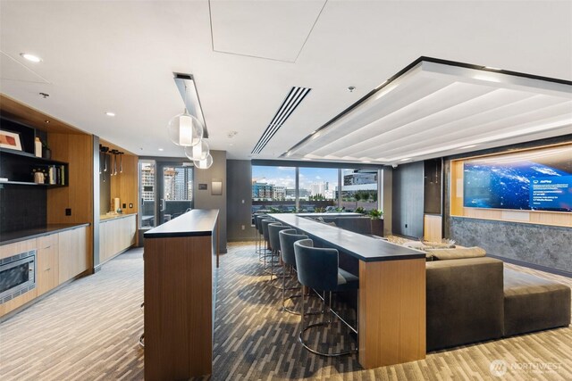 kitchen with modern cabinets, a spacious island, a kitchen breakfast bar, wood finished floors, and dark countertops