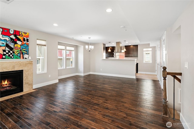 unfurnished living room featuring a chandelier, a fireplace, wood-type flooring, recessed lighting, and baseboards