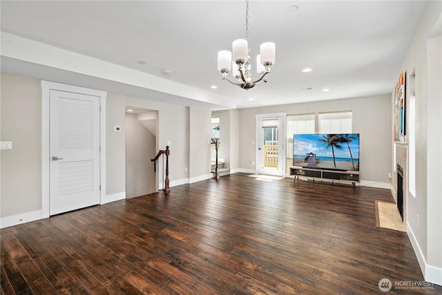 unfurnished living room featuring hardwood / wood-style floors, a chandelier, recessed lighting, and baseboards