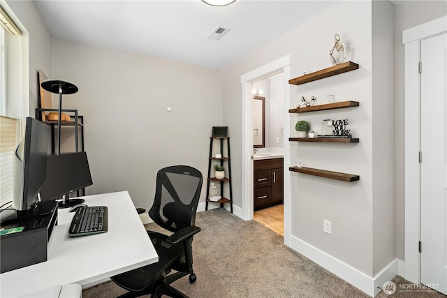 office space with light carpet, baseboards, and a sink