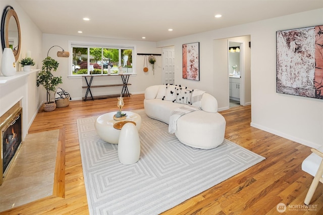 living area featuring recessed lighting, baseboards, a fireplace with flush hearth, and wood finished floors