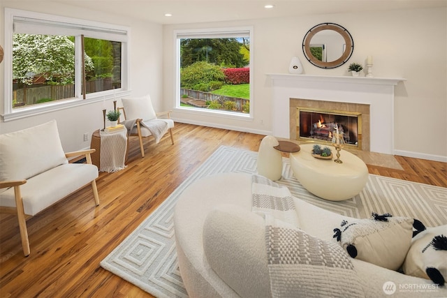 living area featuring recessed lighting, baseboards, a tiled fireplace, and wood finished floors