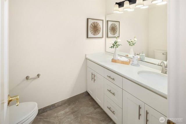 bathroom with double vanity, toilet, baseboards, and a sink