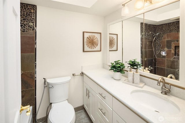 full bathroom with vanity, a tile shower, and toilet