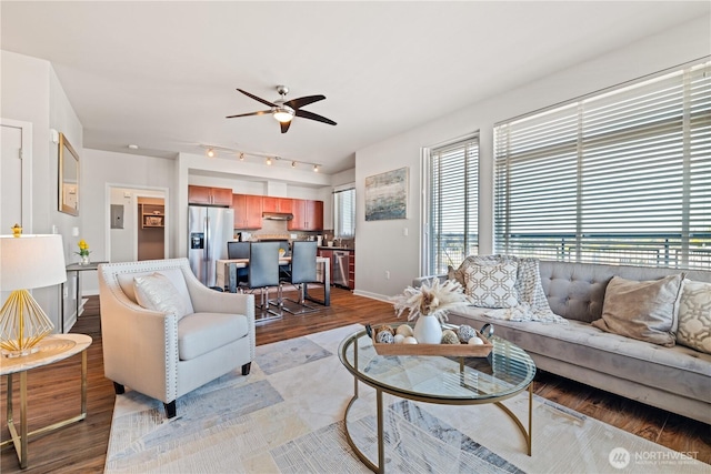 living area featuring track lighting, baseboards, a ceiling fan, and wood finished floors