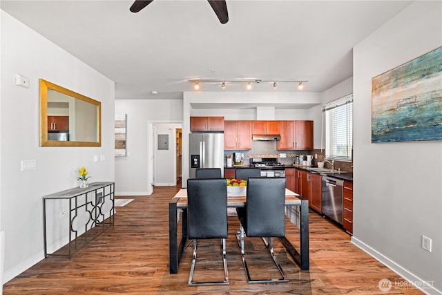 kitchen with ceiling fan, dark countertops, a sink, stainless steel appliances, and tasteful backsplash