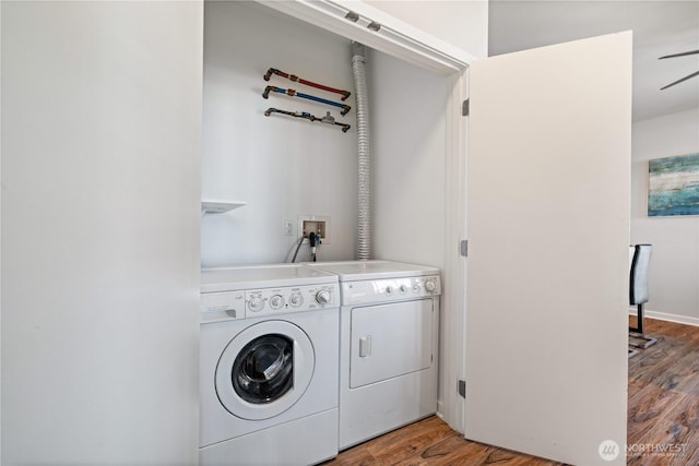 clothes washing area featuring laundry area, a ceiling fan, independent washer and dryer, and wood finished floors