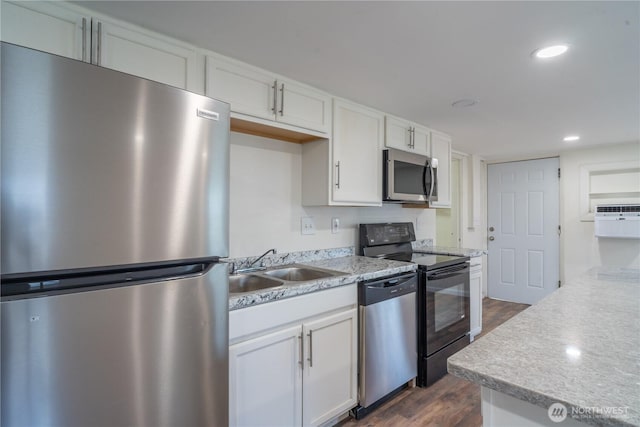 kitchen with white cabinets, appliances with stainless steel finishes, a sink, light countertops, and dark wood-style floors