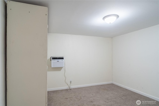 empty room featuring carpet floors, a wall mounted air conditioner, and baseboards