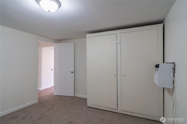 unfurnished bedroom with baseboards, carpet, and a closet