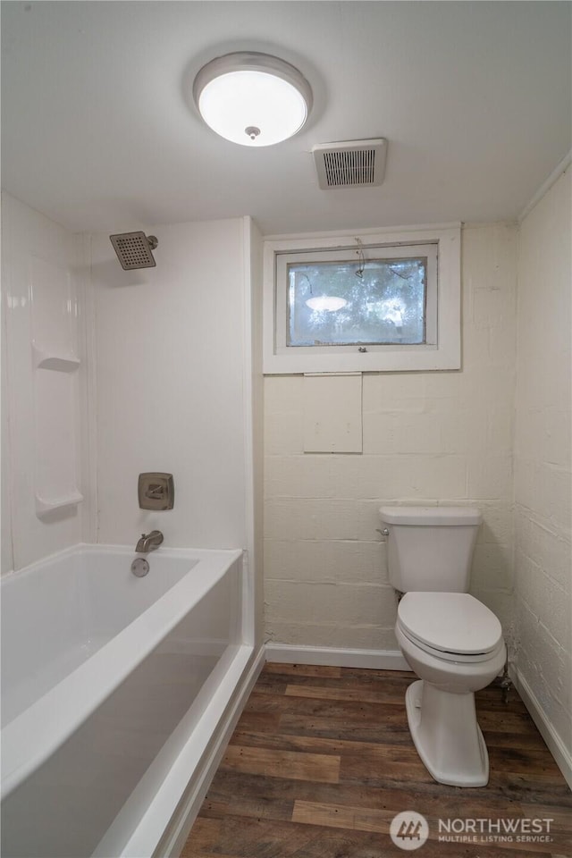 bathroom with visible vents, shower / bathing tub combination, wood finished floors, and toilet