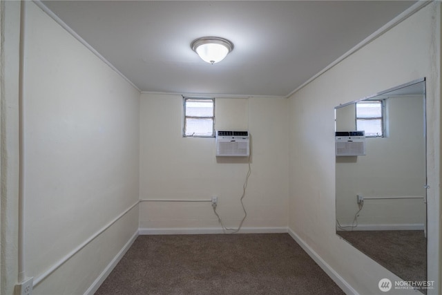 basement featuring carpet flooring, an AC wall unit, baseboards, and a wealth of natural light