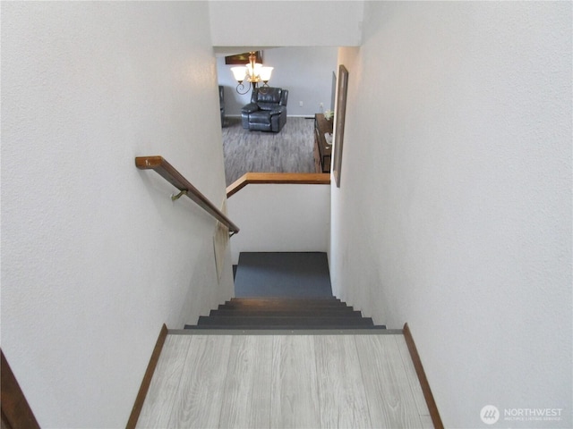 stairway featuring a chandelier and wood finished floors