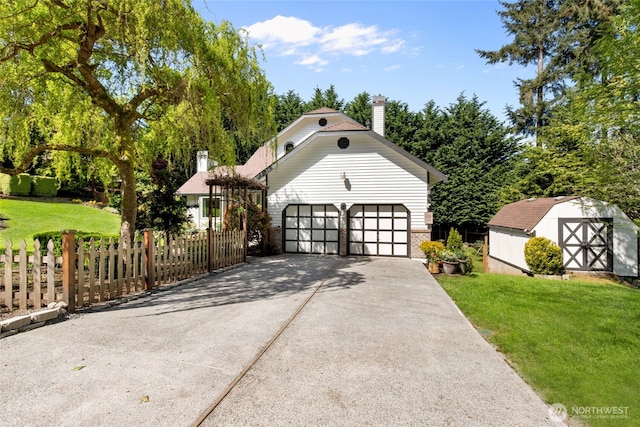 view of front of house with a chimney, fence, an outdoor structure, a front lawn, and an attached garage