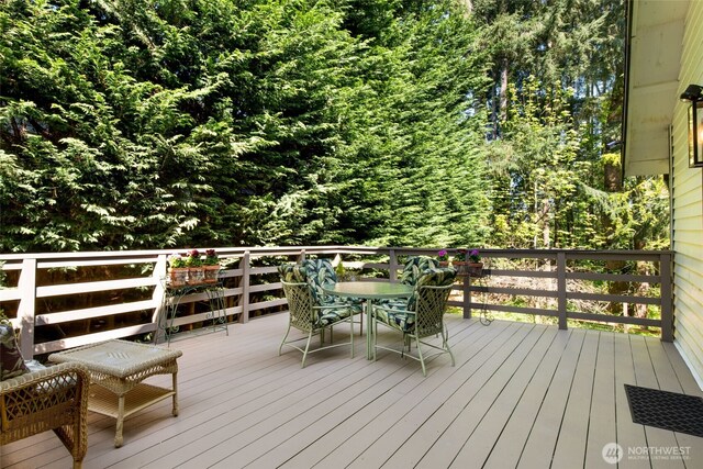 wooden terrace with a forest view and outdoor dining space