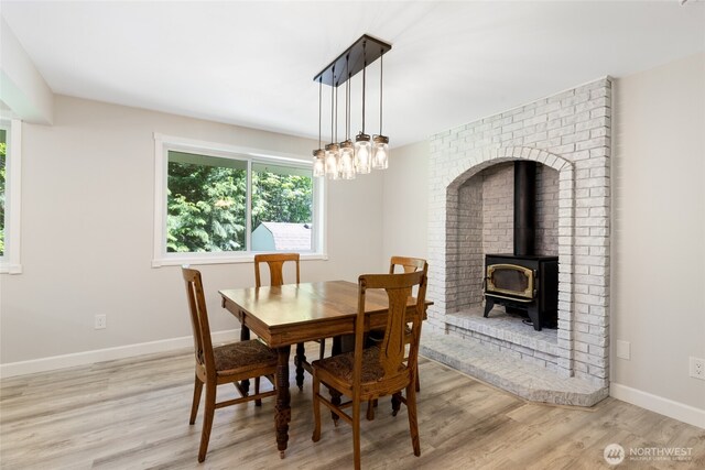 dining room with a healthy amount of sunlight, baseboards, a wood stove, and wood finished floors