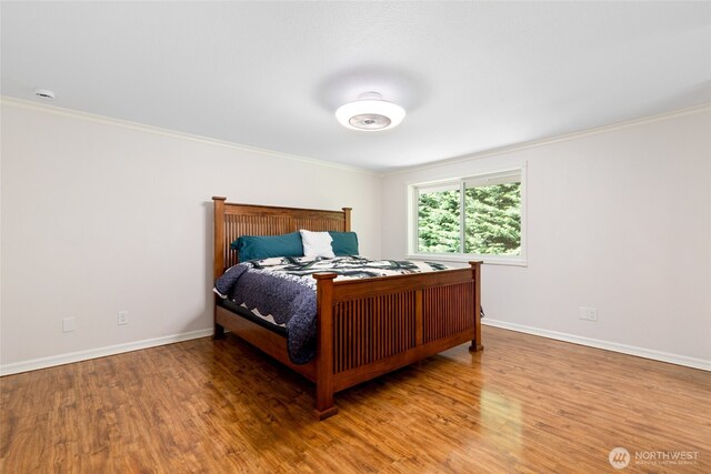 bedroom featuring baseboards, ornamental molding, and wood finished floors