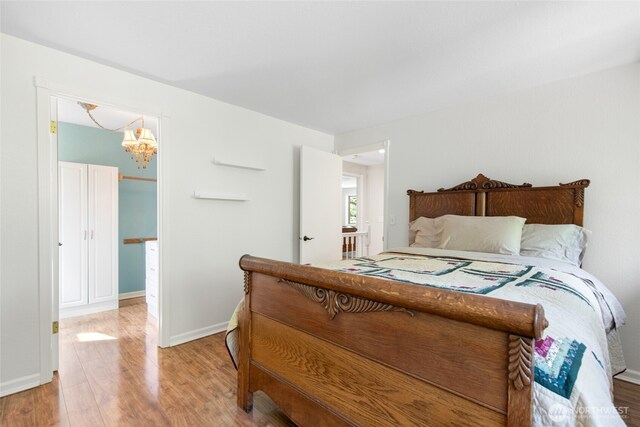 bedroom featuring baseboards, a chandelier, and wood finished floors