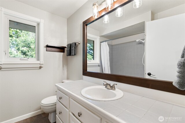 full bathroom with baseboards, a shower with curtain, toilet, and vanity