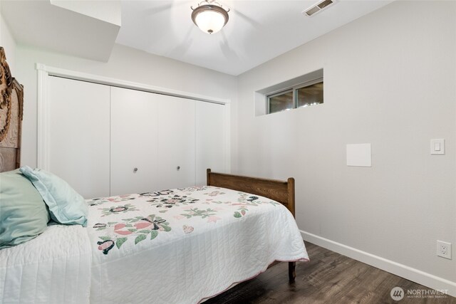 bedroom with baseboards, visible vents, wood finished floors, and a closet