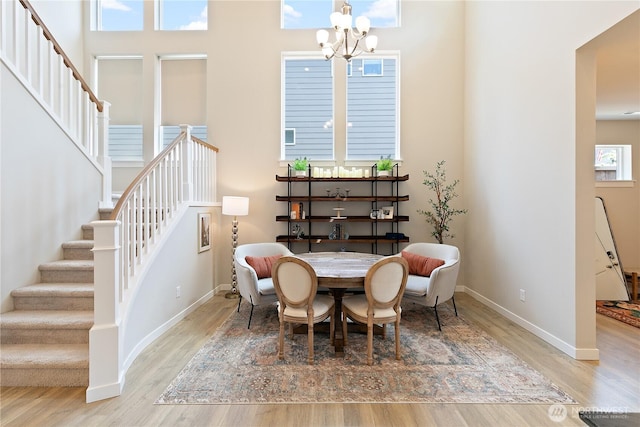 dining area featuring an inviting chandelier, baseboards, wood finished floors, and stairway