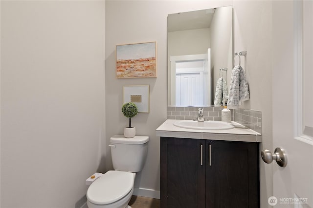 half bath featuring backsplash, toilet, and vanity