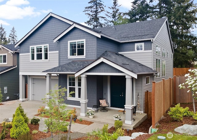 craftsman-style house with fence, a shingled roof, an attached garage, a porch, and driveway