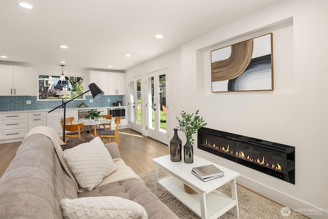 living room with a glass covered fireplace, light wood-type flooring, and recessed lighting
