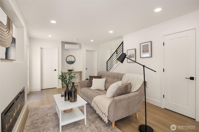 living area featuring recessed lighting, baseboards, light wood-style flooring, and a wall mounted air conditioner