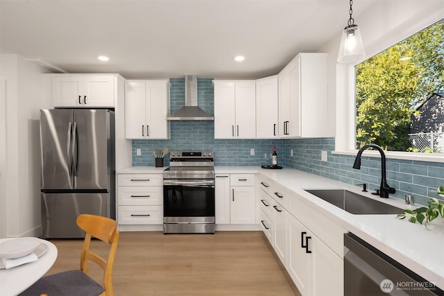 kitchen featuring wall chimney range hood, light countertops, tasteful backsplash, a sink, and stainless steel appliances