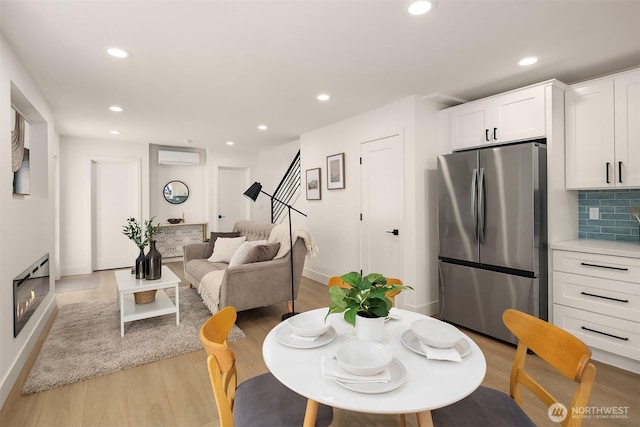 dining room with baseboards, recessed lighting, light wood-style floors, and a wall mounted air conditioner