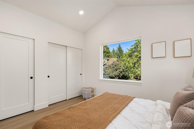 bedroom featuring recessed lighting, high vaulted ceiling, multiple closets, and light wood-style flooring