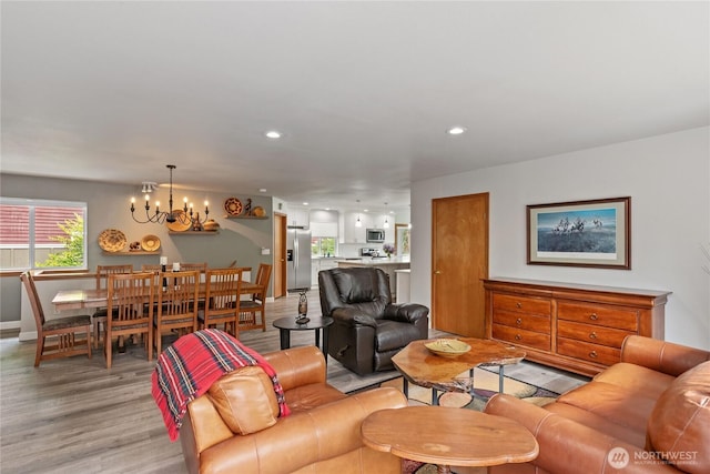 living area with recessed lighting, light wood-style flooring, and a notable chandelier