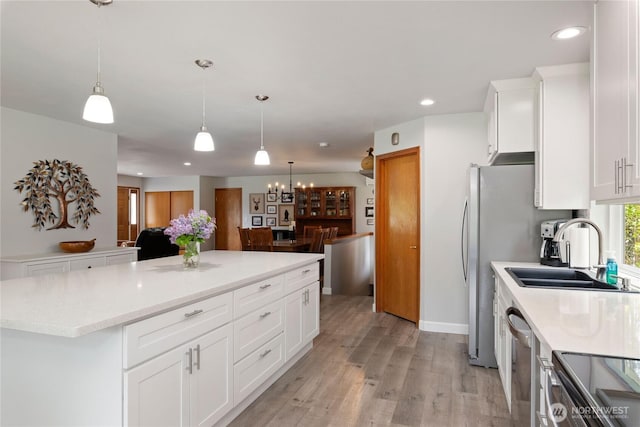 kitchen with a sink, light countertops, a notable chandelier, stainless steel appliances, and recessed lighting