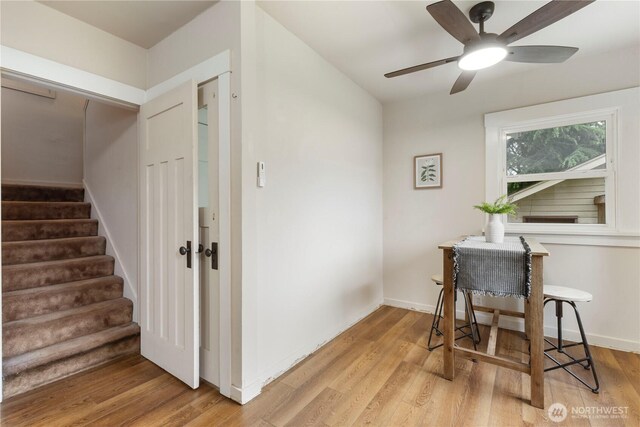 interior space featuring a ceiling fan, baseboards, and light wood-style flooring