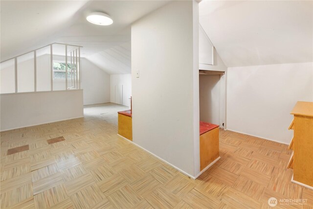 additional living space featuring baseboards and lofted ceiling