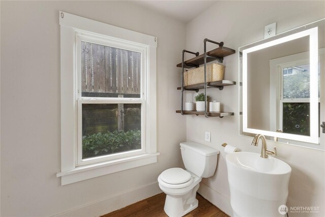 half bathroom featuring baseboards, wood finished floors, and toilet