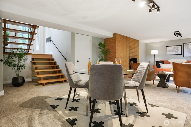 15506 Juanita Dr NE, Kenmore, WA 98028 - carpeted dining room featuring visible vents, a brick fireplace, and stairway