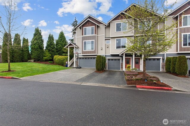 view of property with board and batten siding, driveway, a garage, a front lawn, and stone siding