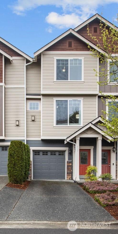 multi unit property featuring a garage, aphalt driveway, and stone siding