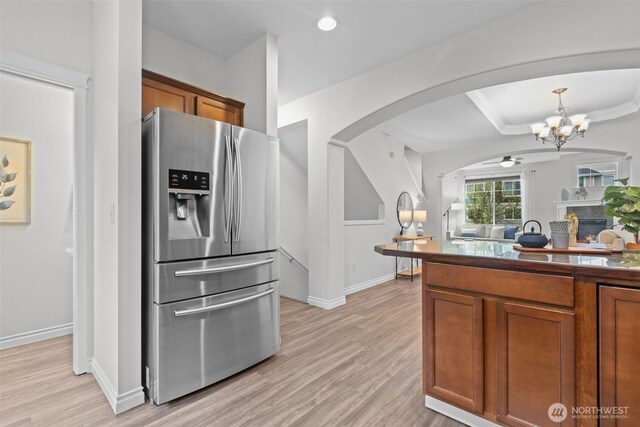 kitchen featuring brown cabinetry, a chandelier, stainless steel fridge, and light wood-style floors